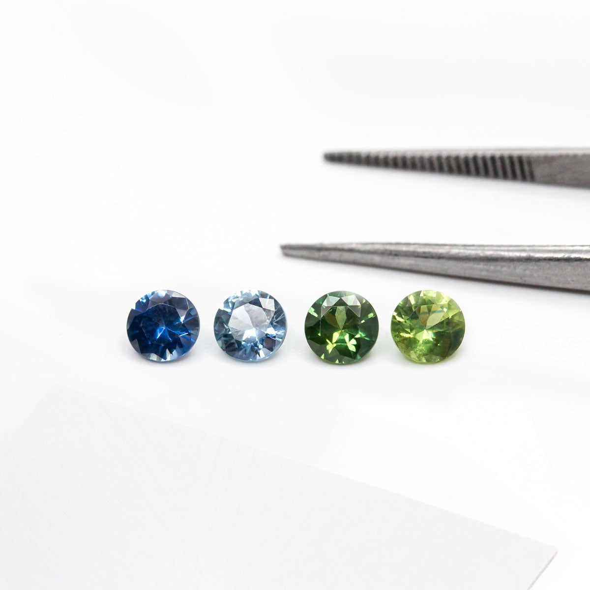 Saphirs éthiques certifiés Fair Trade en bleu clair, bleu foncé, vert clair et vert foncé, présentés seuls et sertis sur des bagues de fiançailles en or, Paulette à Bicyclette