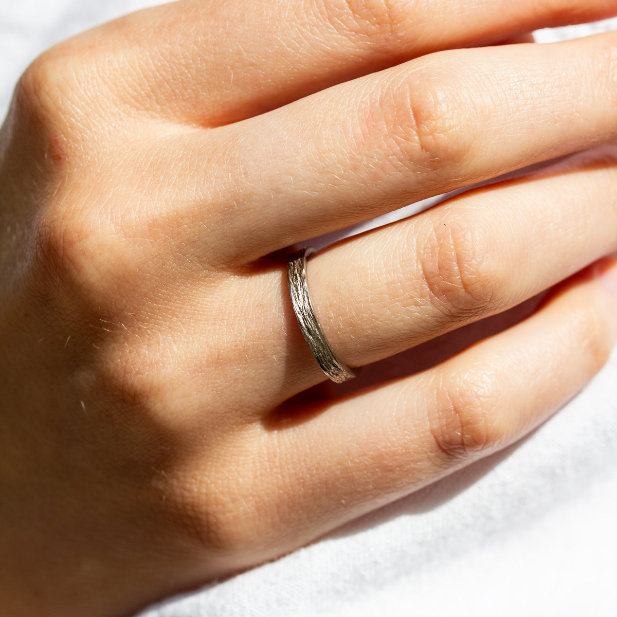 Alliance fine en or 750/1000 certifié Fairmined, fabriquée dans notre atelier parisien et ornée d’une texture inspirée de l’écorce d’amandier.