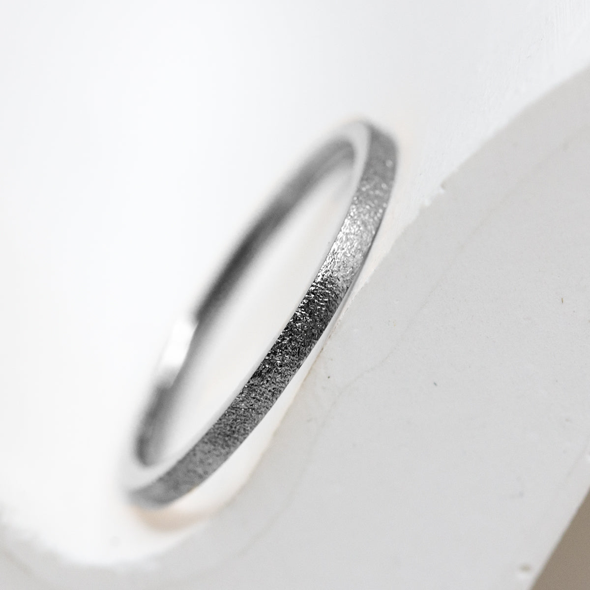 Alliance fine et discrète avec une texture martelée réalisée en or gris palladié dans notre joaillerie artisanal.