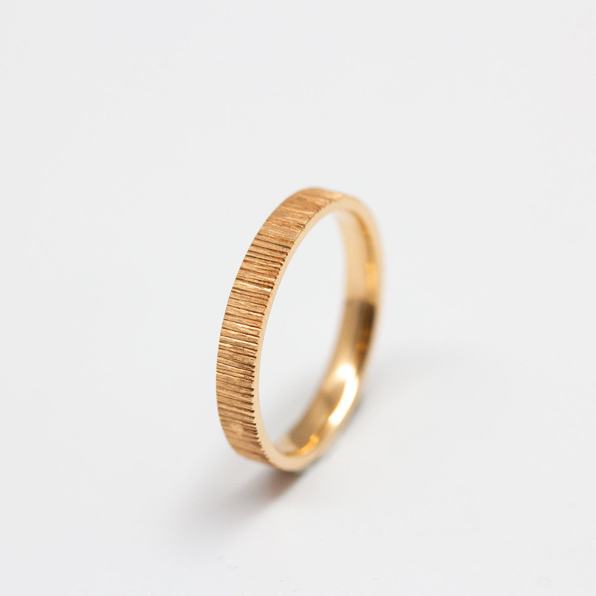 Alliance originale femme en or rouge recyclé et prime Fairmined, texture strié et fabrication artisanale dans notre atelier de joaillerie à Paris. Joaillier éthique