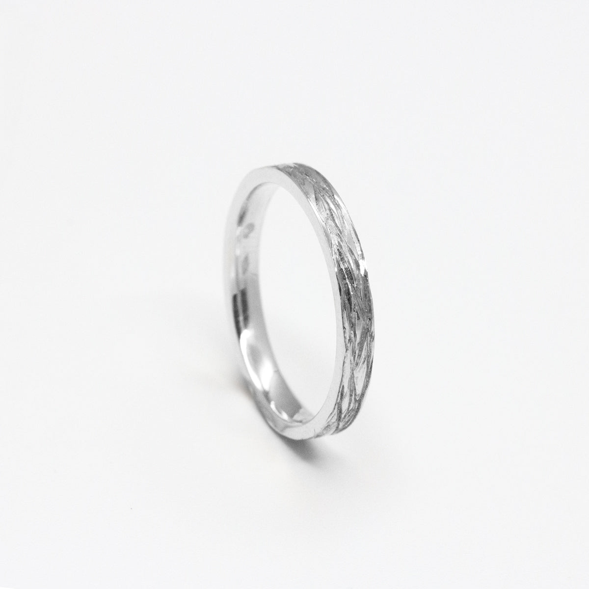 Alliance fine en or blanc 18 carats, confectionnée dans notre atelier à Paris, et ornée d’une texture rappelant l’écorce d’amandier.