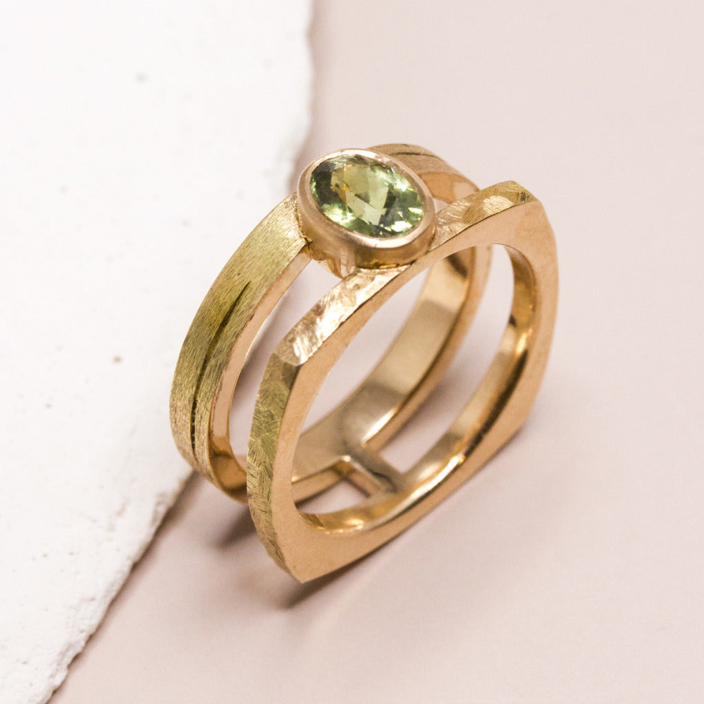 Bague double anneau en or ornée d'un zircon vert ovale.