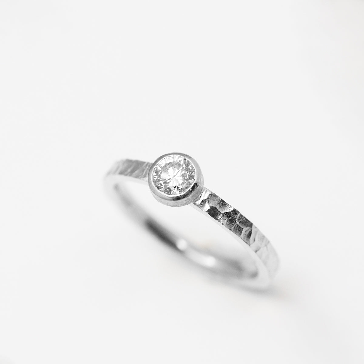 Bague solitaire éthique en or blanc 18 carats et diamant de synthèse en serti clos, réalisée dans un atelier de joaillerie à Paris.