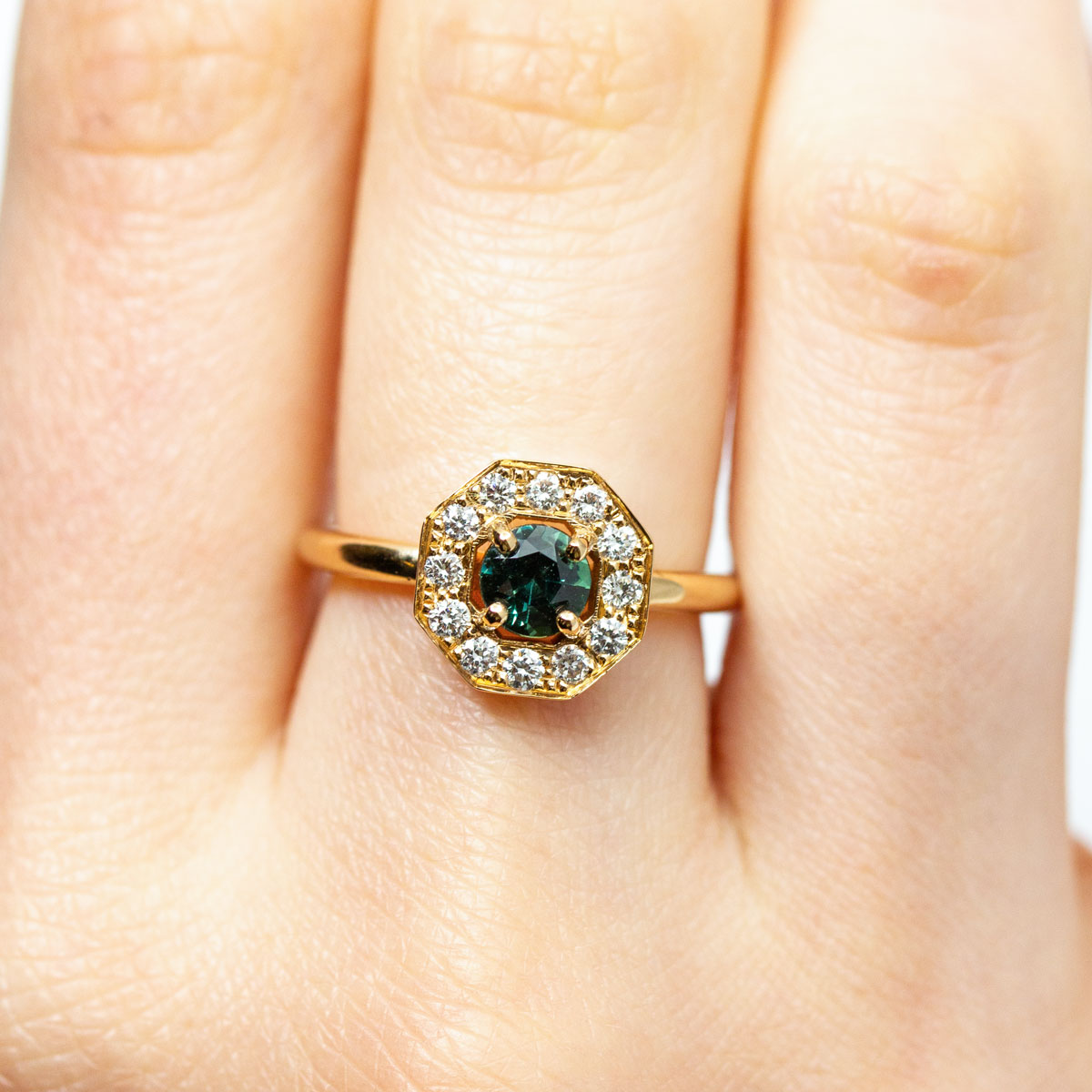 Pièce unique - Bague de fiançailles promesse Art Déco géométrique Leone XL portée, sertie d'un saphir Teal bleu-vert entouré de 16 diamants de synthèse en or rose-champagne recyclé 18 carats. Disponible taille 53, réalisée à Paris dans notre atelier de joaillerie