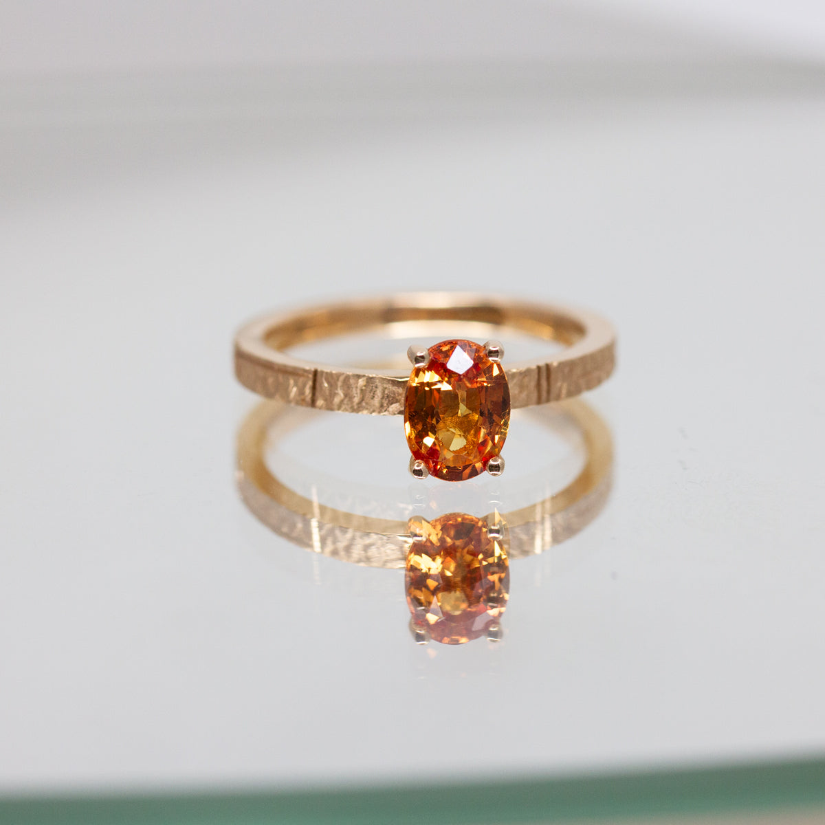 Bague solitaire revisité en or rose-champagne recyclé 18 carats sertie d'un saphir orange.