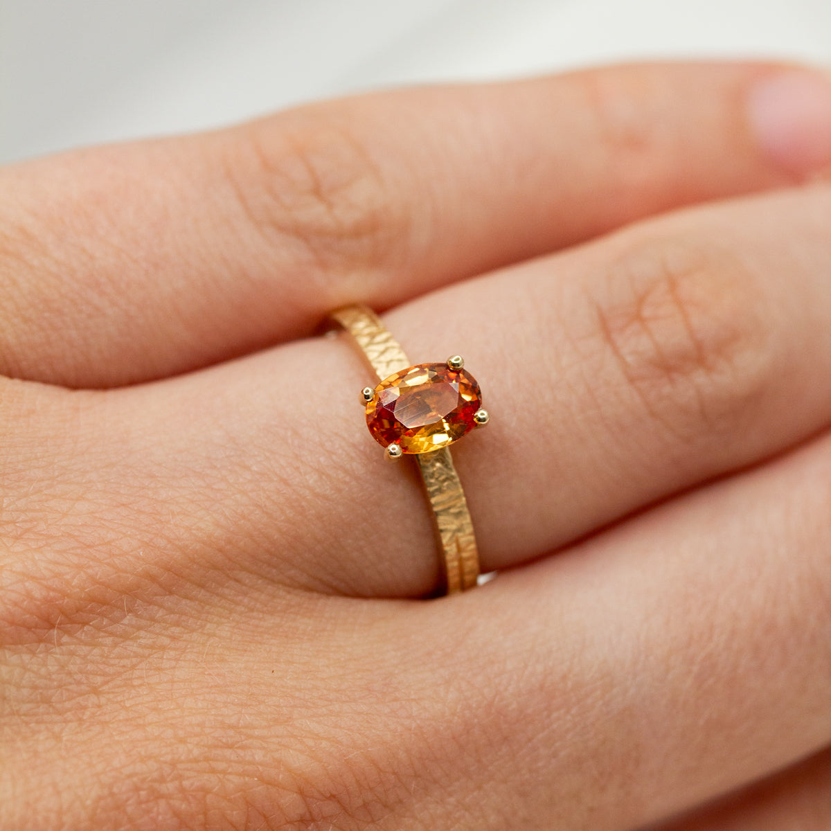 Bague solitaire sertie d'un saphir orange en or rose-champagne 18 carats recyclé.