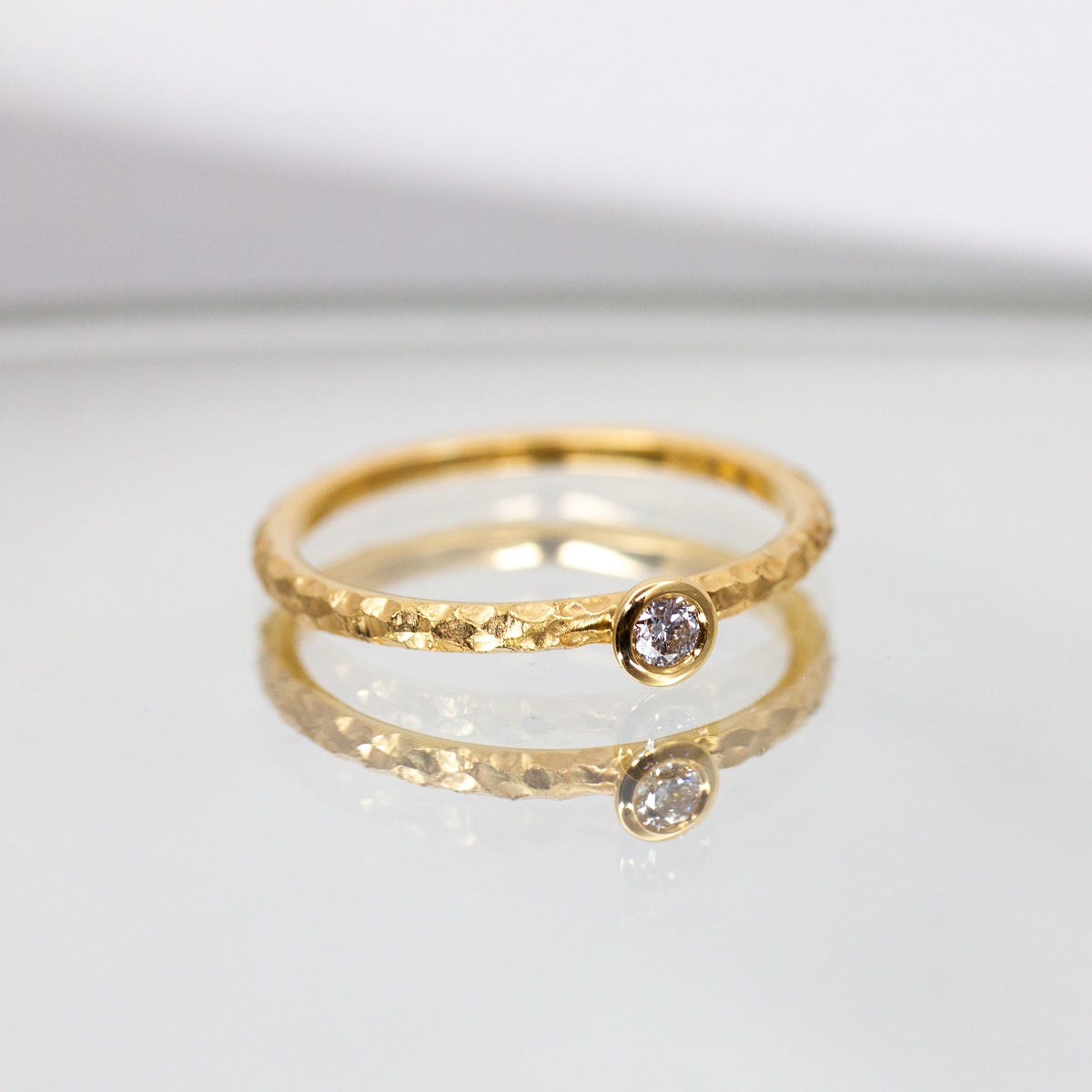 Bague fine et délicate sertie d'un diamant en son centre avec un anneau effet martelé en or jaune 18 carats Fairmined.