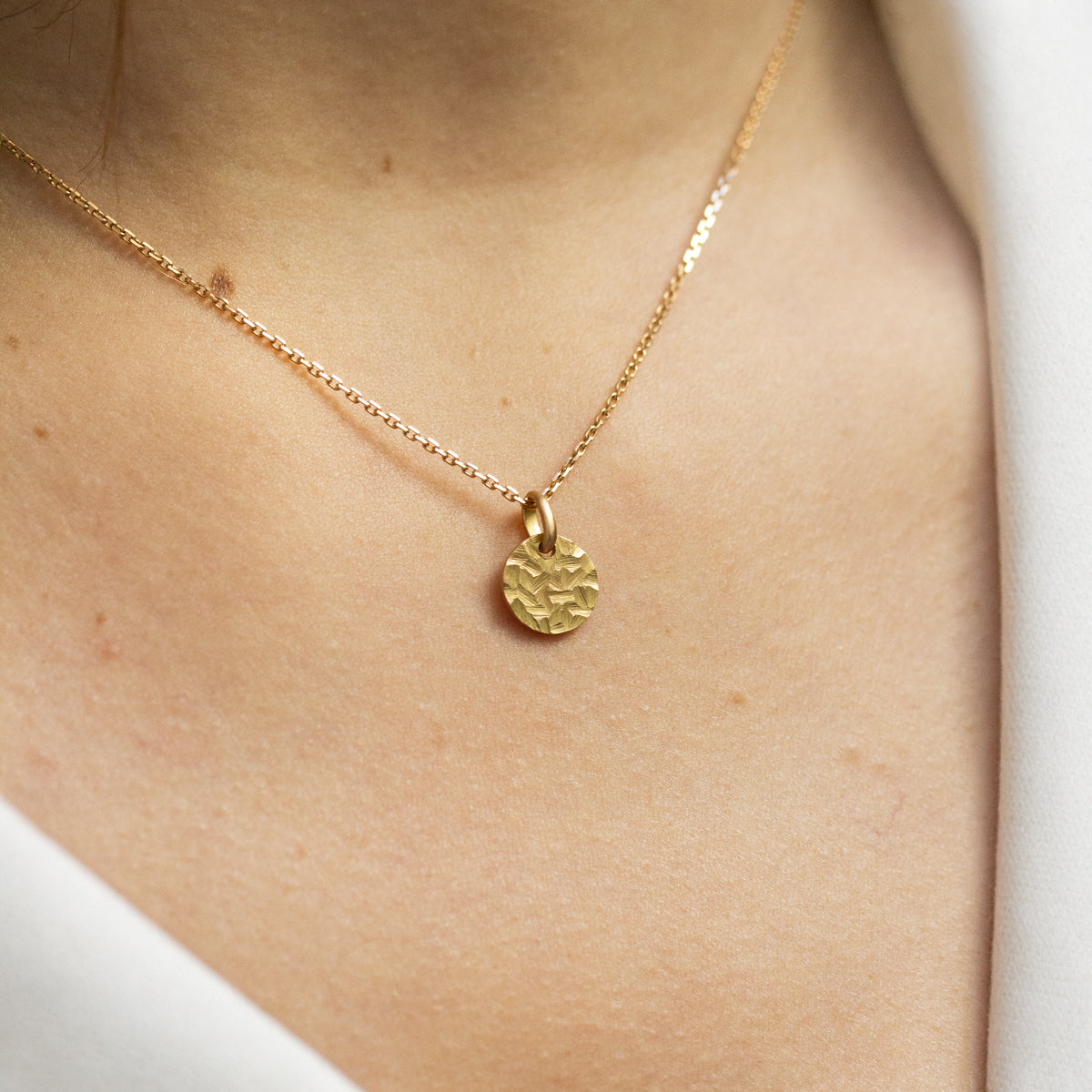 Médaille ronde de 10mm pour femme en or jaune 750/1000 martelé artisanalement dans notre atelier de joaillerie éthique. Bijou à offrir pour les baptêmes, naissances, anniversaires