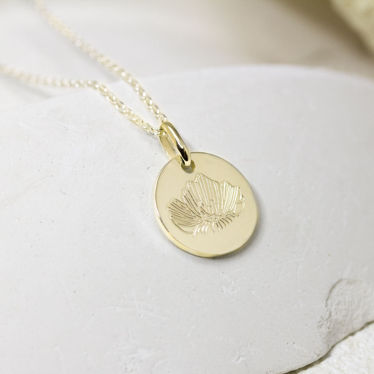 Médaille en or jjaune avec gravure fleur made in France.