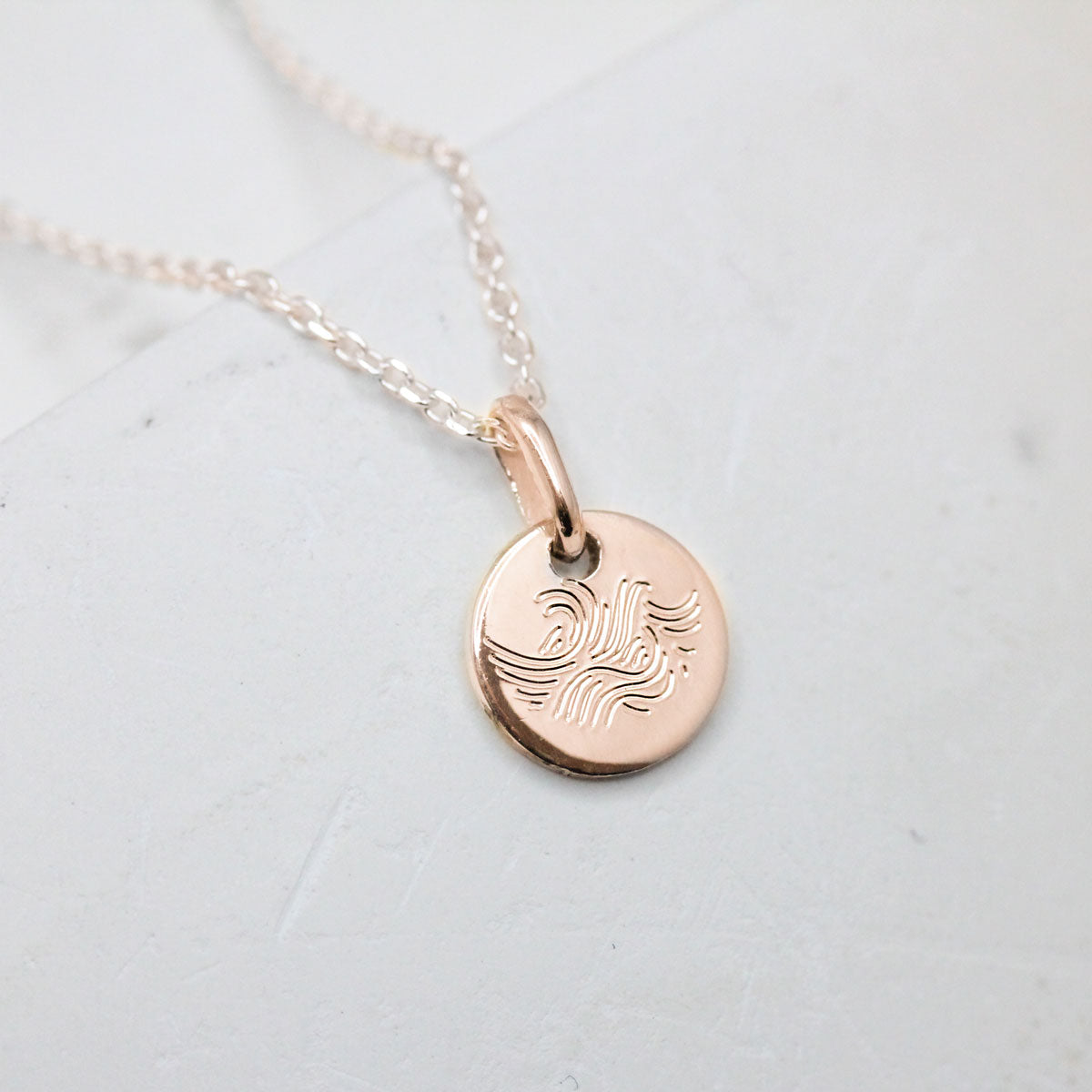 Médaille vague en or rouge éthique, joaillerie artisanale.