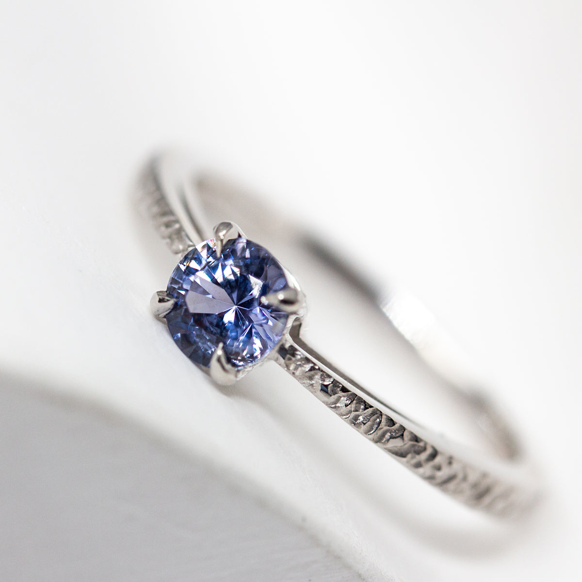 Bague solitaire avec en son centre un saphir violet de Tanzanie et un anneau texturé en or blanc Fairmined 18 carats.