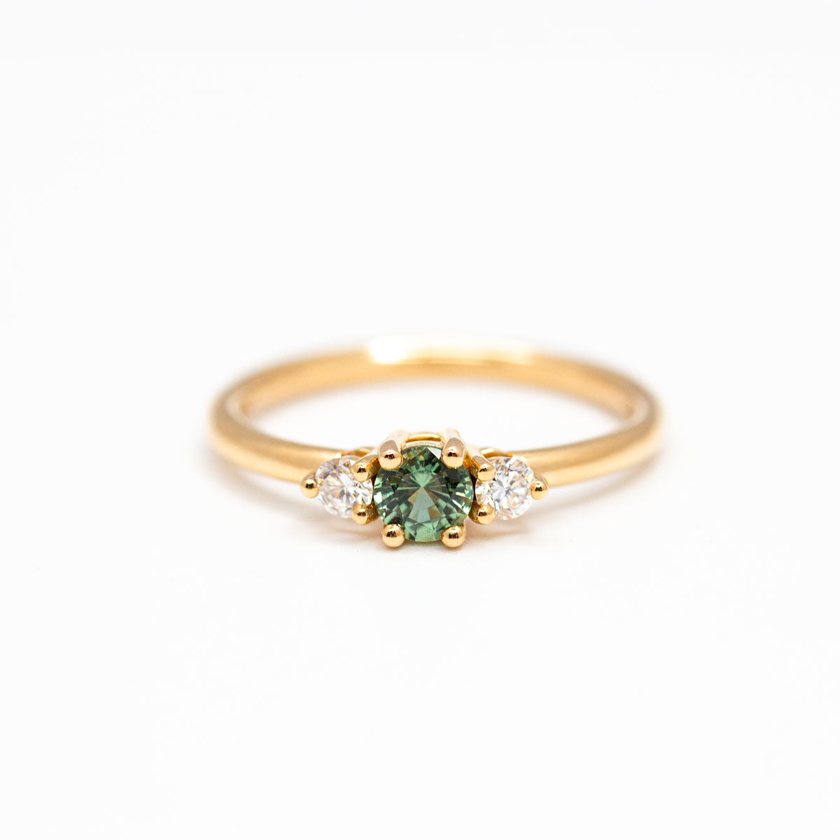 Bague de fiançailles épaulée femme Soleine en or jaune 18 carats recyclé ornée d'un saphir vert et deux diamants de synthèse ronds. Réalisée à la main dans notre atelier de joaillerie à Paris