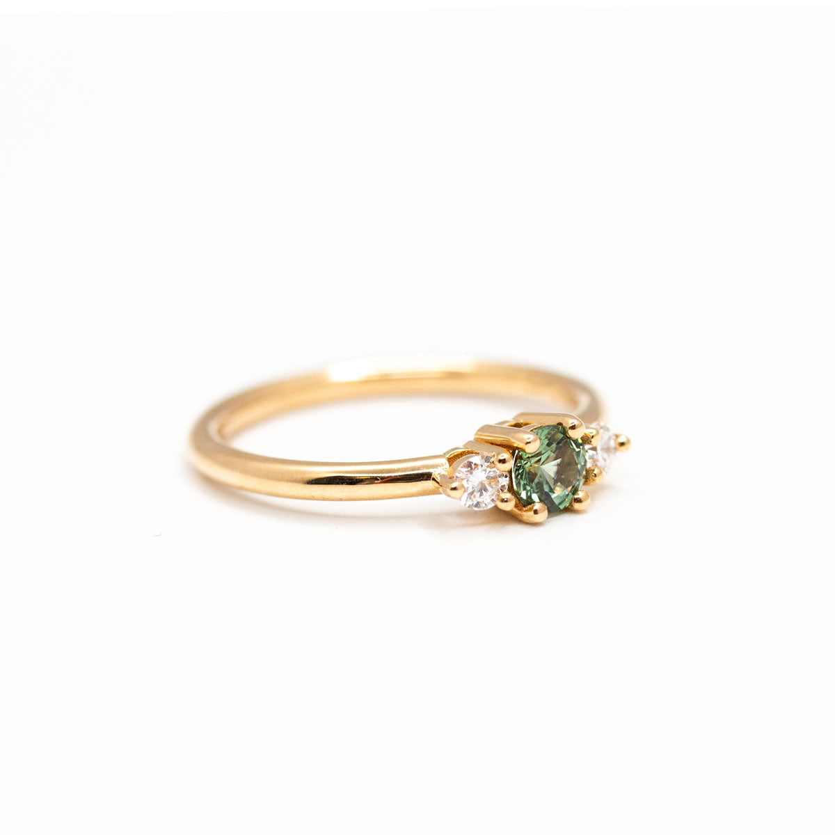 Bague de fiançailles épaulée femme Soleine en or jaune 18 carats recyclé ornée d'un saphir vert et deux diamants de synthèse ronds. Réalisée à la main dans notre atelier de joaillerie à Paris