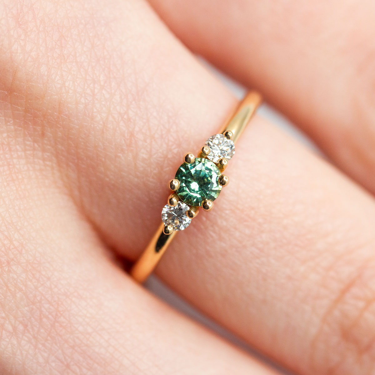 Bague de fiançailles épaulée femme Soleine en or jaune 18 carats recyclé ornée d'un saphir vert et deux diamants de synthèse ronds. Réalisée à la main dans notre atelier de joaillerie à Paris