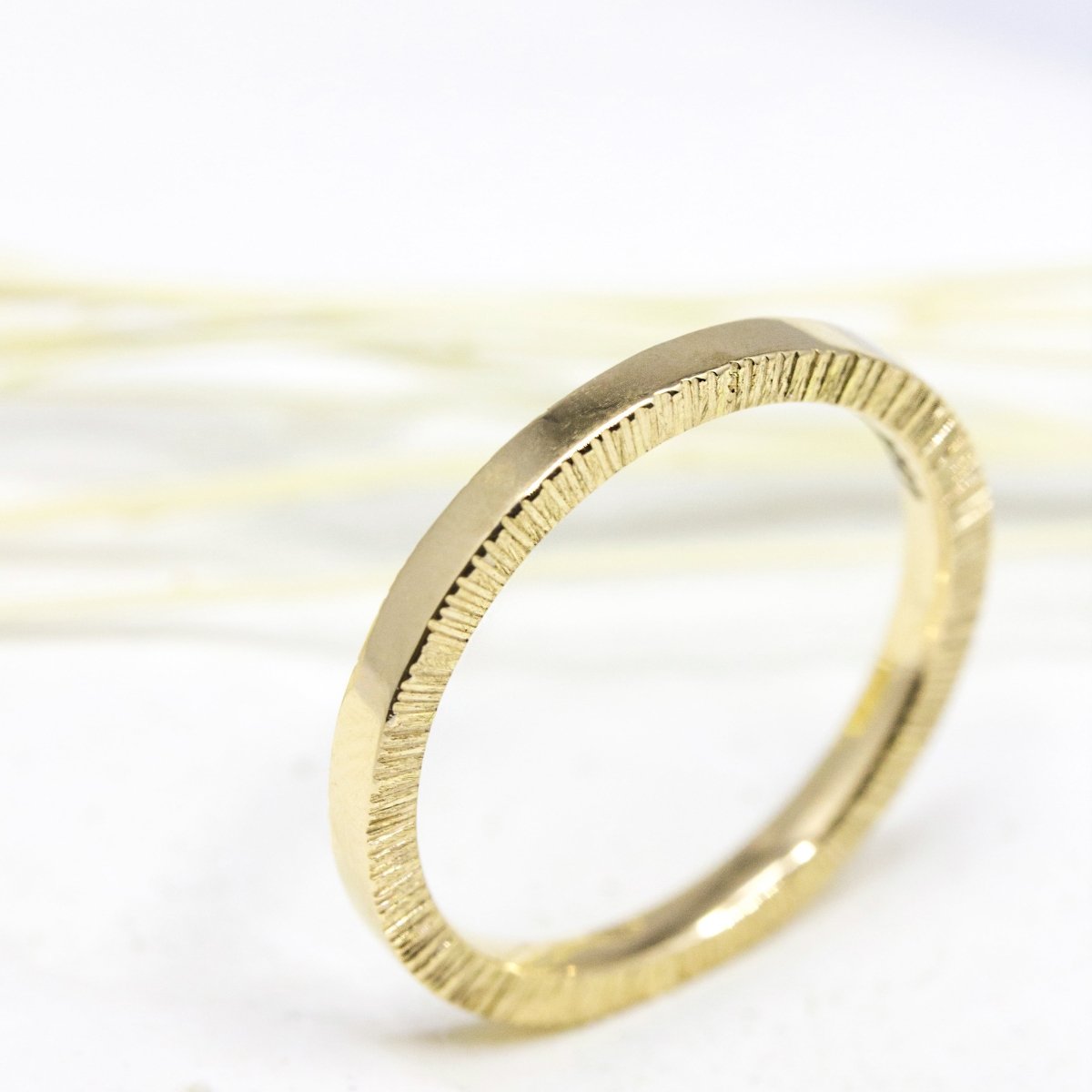 Alliance en or jaune, lisse en surface et texturée sur les côtés.