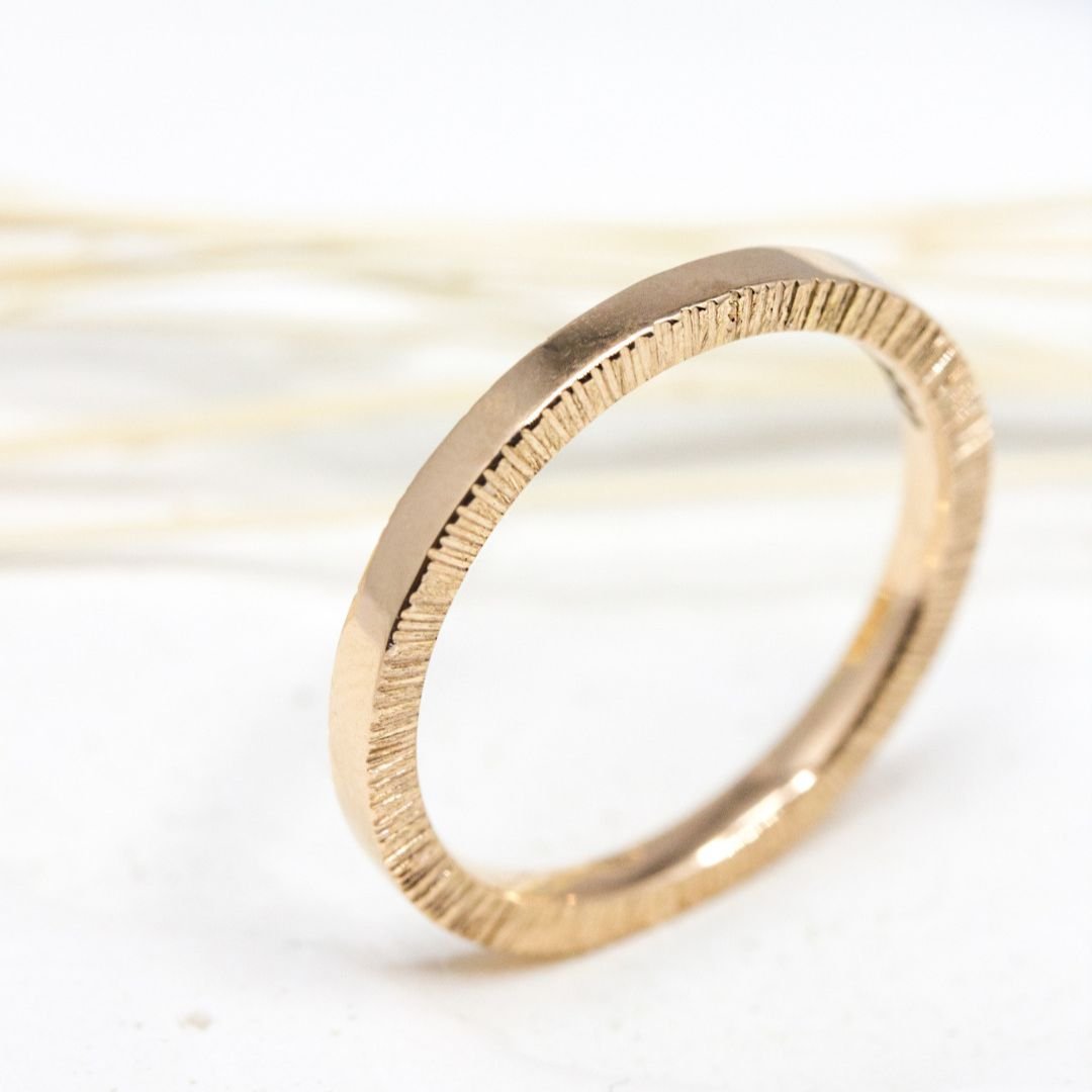 Alliance en or rose-champagne, lisse en surface et texturée sur les côtés.