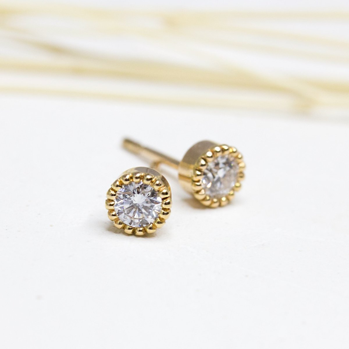Boucles d'oreille Madeleine en or jaune 18 carats Fairmined. Elles sont ornées d'un serti millegrain et de deux diamants de synthèse.