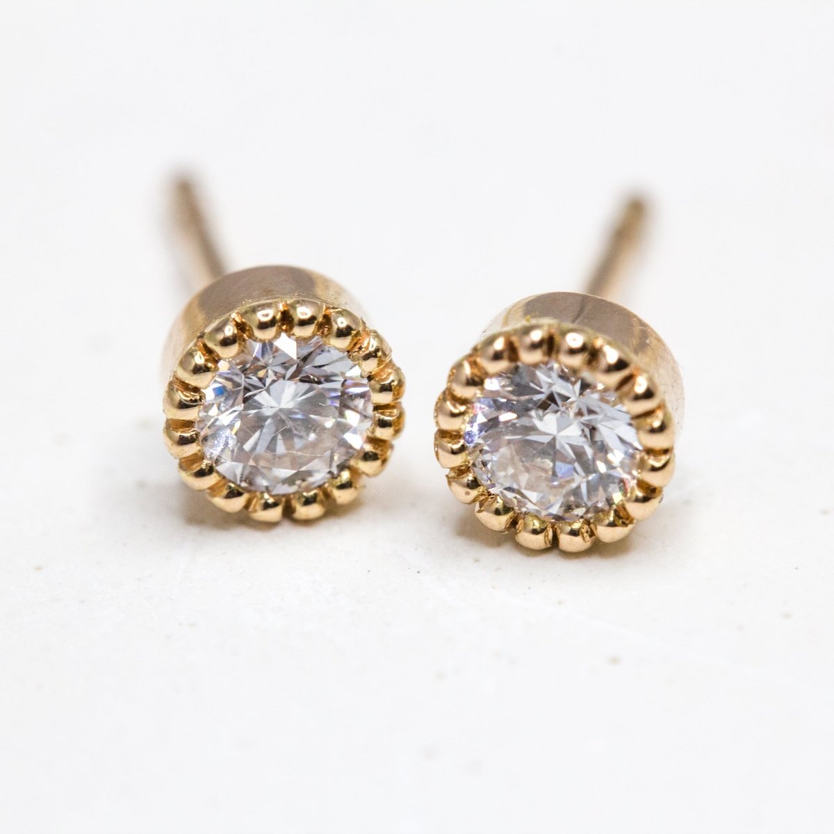 Boucles d'oreille Madeleine en or rose-champagne 18 carats Fairmined. Originales, elles sont ornées d'un serti millegrain et de deux diamants de synthèse.