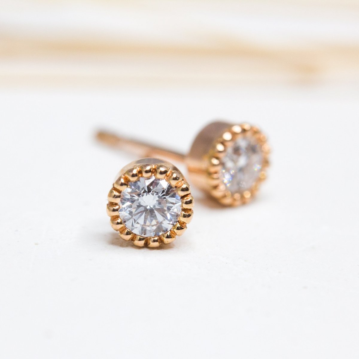 Boucles d'oreille Madeleine en or rouge 18 carats Fairmined. Légères, elles sont ornées d'un serti millegrain et de deux diamants de synthèse.