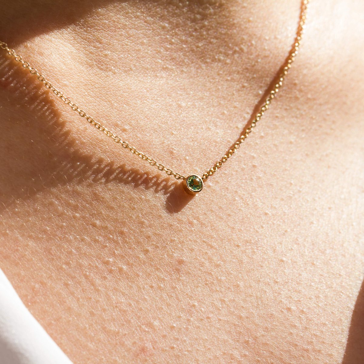 Collier original en or rose Fairmined orné d'une pierre verte au centre.