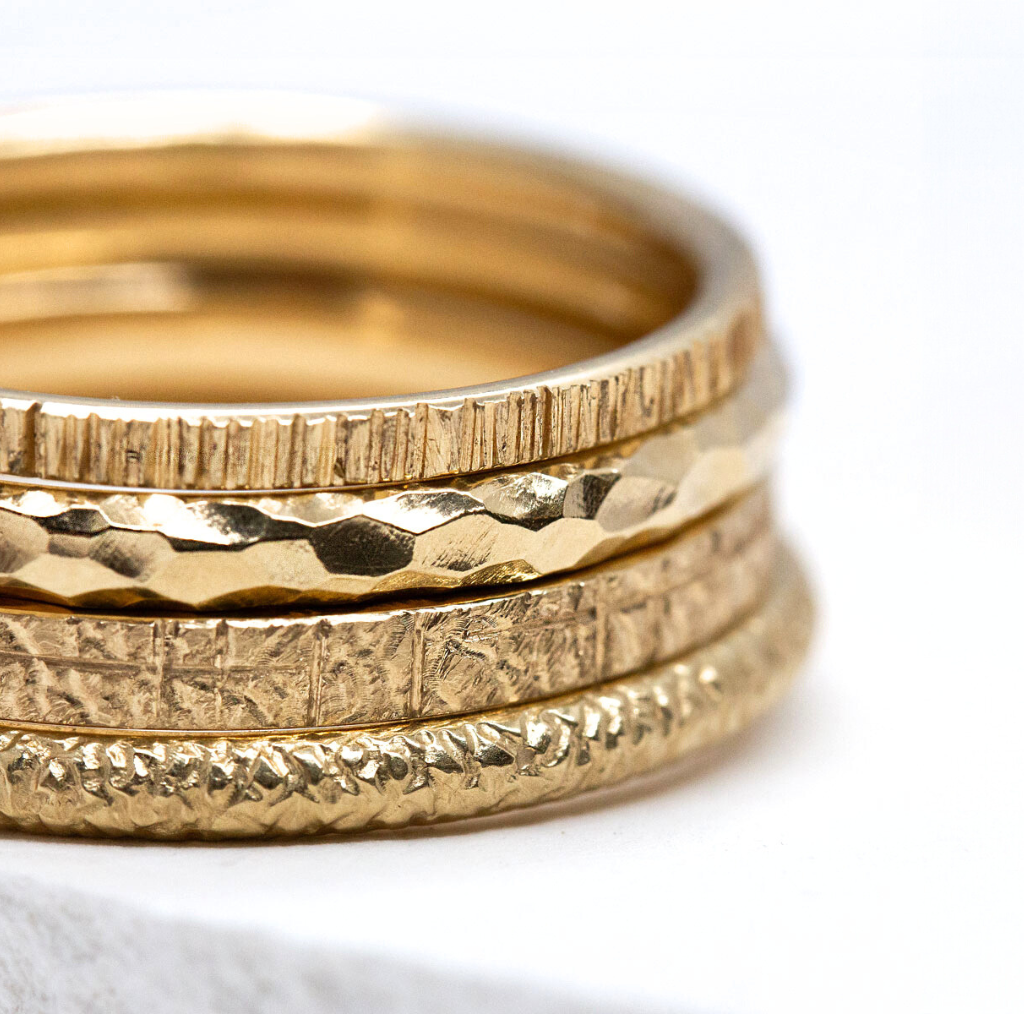 Alliances éthiques en or Fairmined empilées, montrant les textures martelées, gravées et lisses de Paulette à Bicyclette