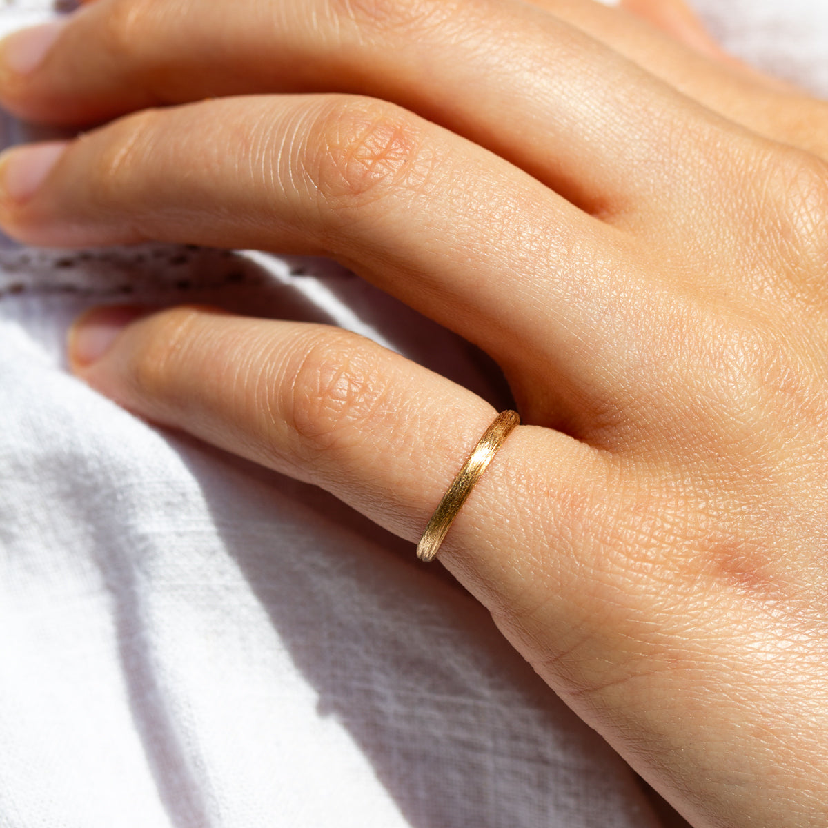 Alliance en or jaune au fini brossé, née des mains d’artisans dans une joaillerie éthique au cœur de Paris.