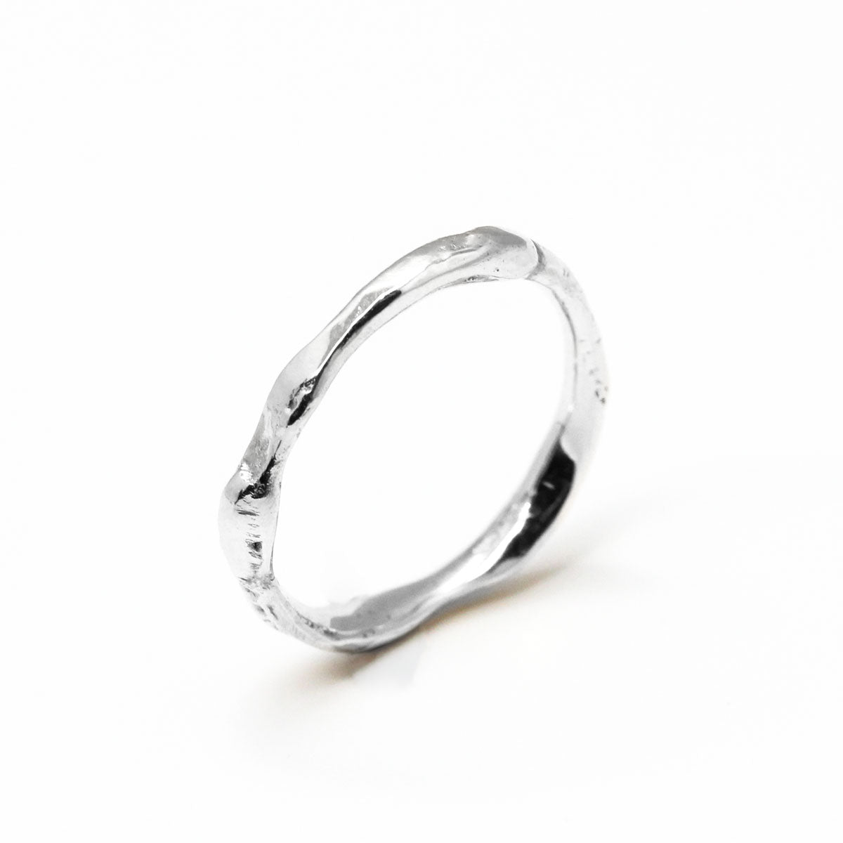 Alliance bague de mariage ondulée femme et homme en or blanc 750/1000 recyclé + prime Fairmined, avec une texture brute et unique qui rappelle l’or fondu, fabriquée artisanalement à Paris dans une joaillerie éthique.