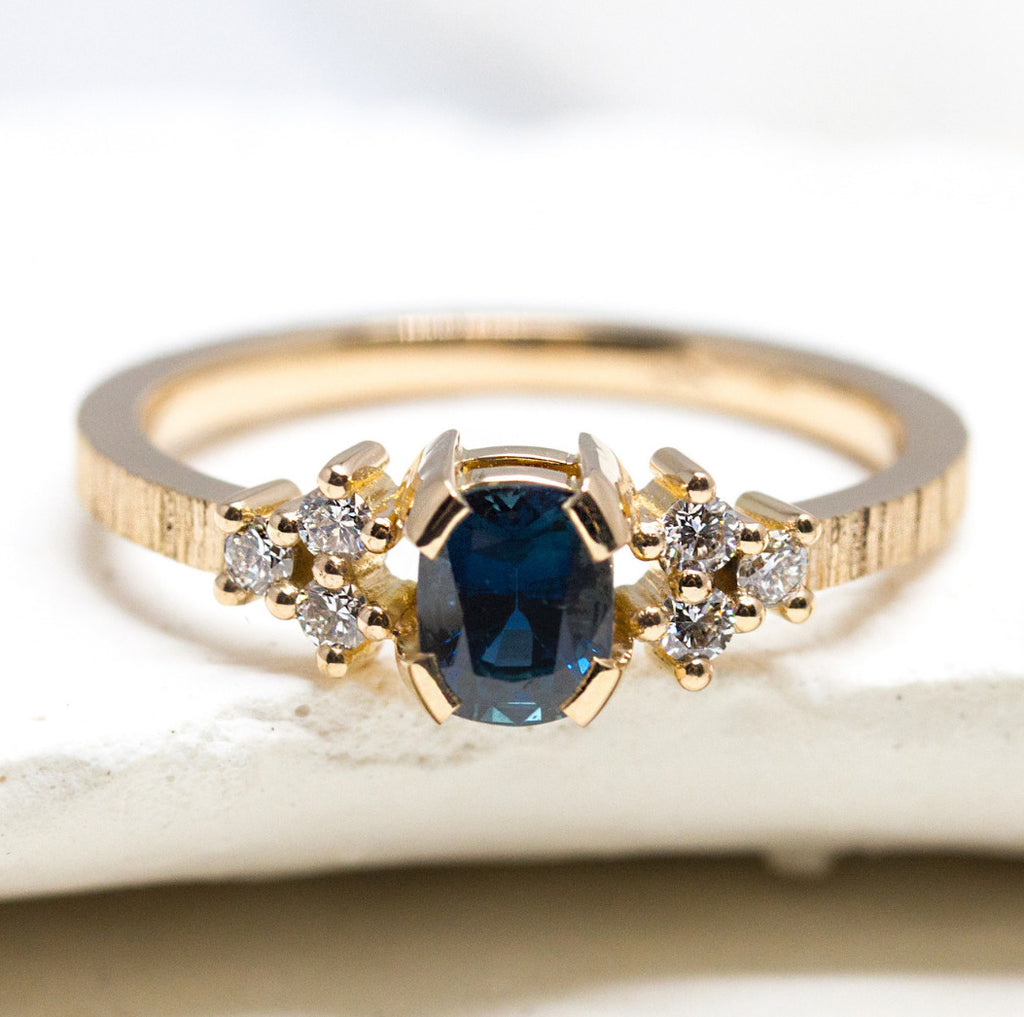 Bague de fiançailles en or ornée de six diamants et d'un saphir bleu.