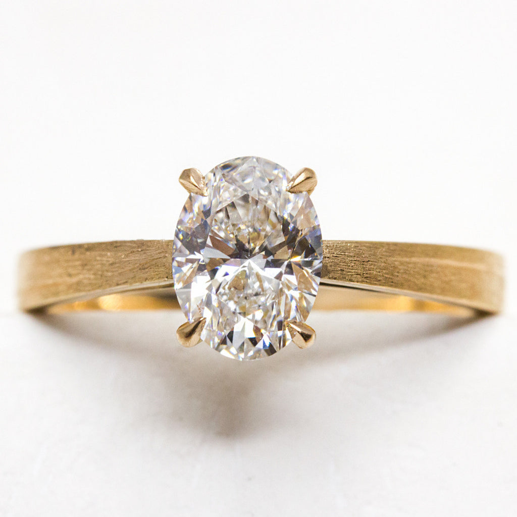 Bague de fiançailles en or 18 carats ornée d'un diamant de synthèse ovale.