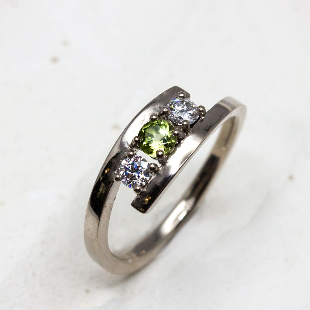 Bague de fiançailles originale ornée d'une periodt verte et de diamants de synthèse.