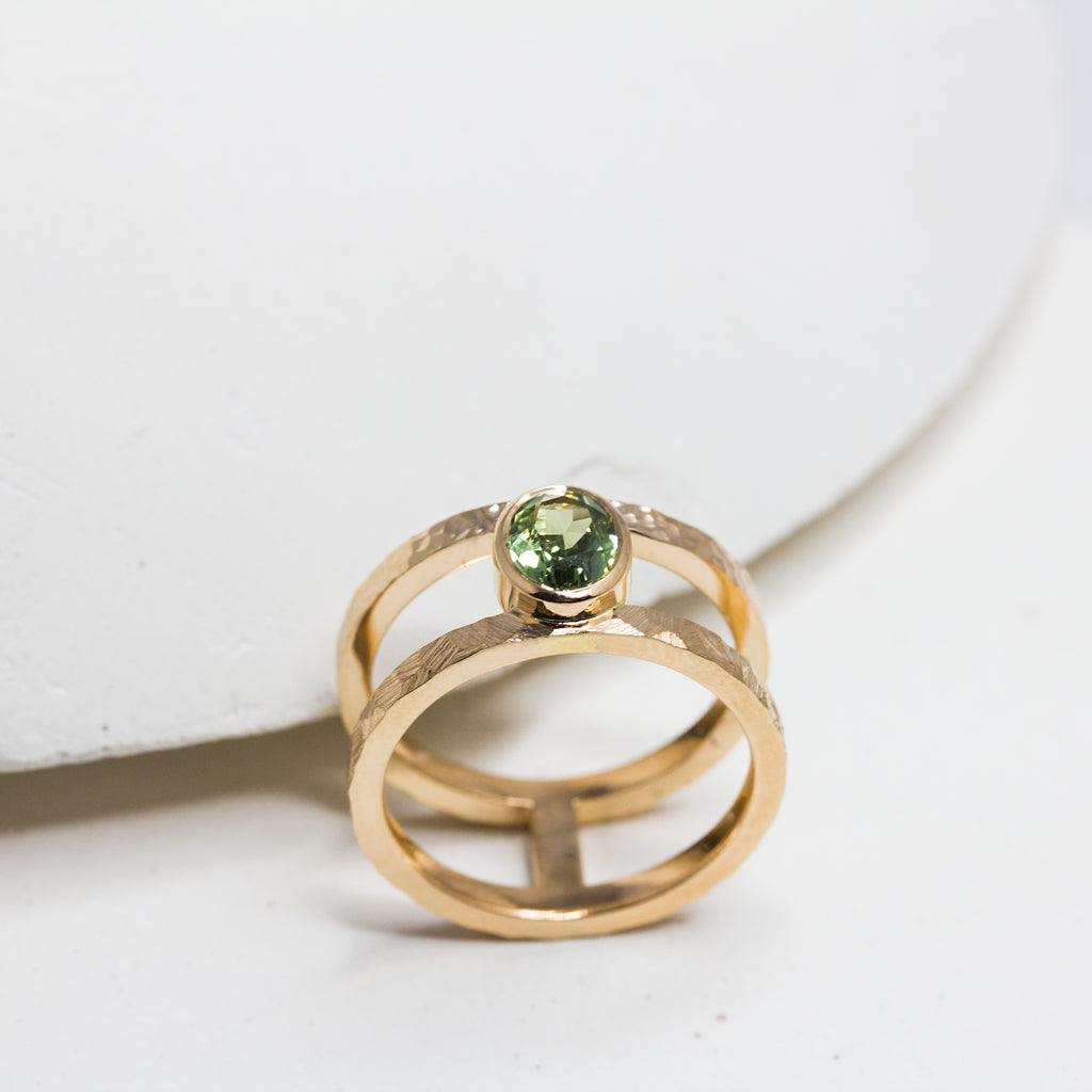 Bague en or artisanale de fabrication française. Elle est composée de deux anneaux et d'un saphir vert.
