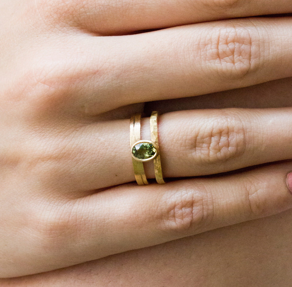Bague originale double anneau en or ornée d'un zircon vert au centre.