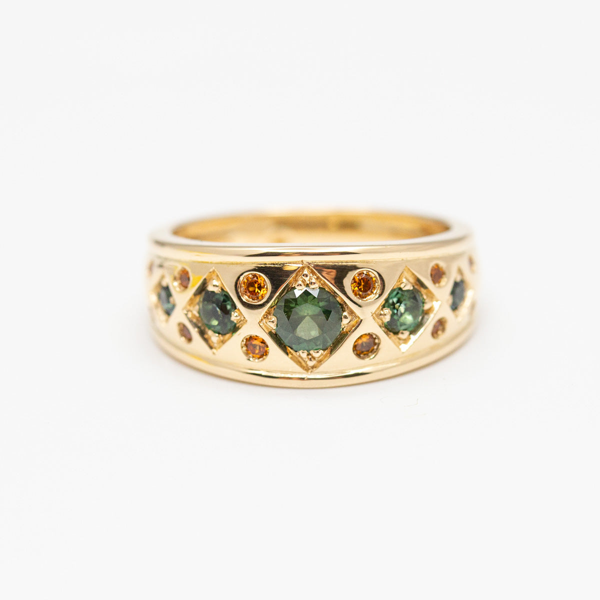 Bande bandeau sur mesure en or jaune 750/1000 éthique sertis d'un saphir vert d'Auvergne central et d'un pavage de granats spesartites. Bague de fiançailles créée dans notre atelier de joaillerie indépendant à paris