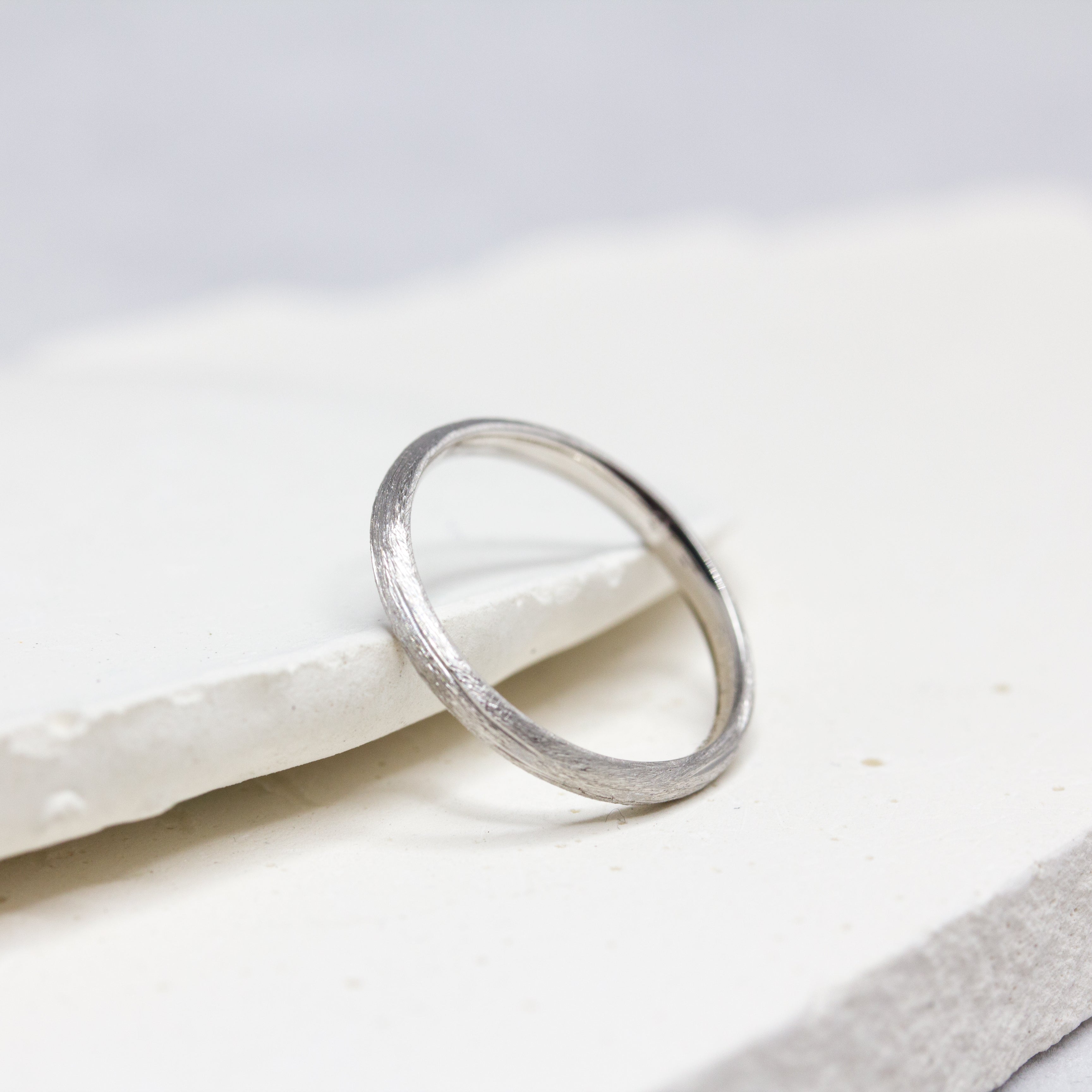 Alliance Casildée fine en or blanc 18 carats Fairmined, à la texture brossée, confectionnée avec soin dans notre atelier de joaillerie éthique à Paris.