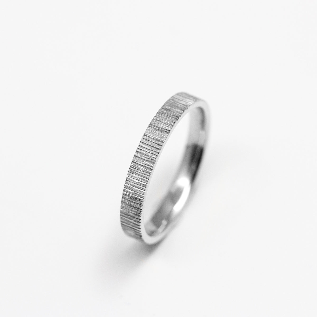 Alliance originale homme en or blanc recyclé et prime Fairmined, texture stries et fabrication artisanale dans notre atelier de joaillerie à Paris. Joaillier éthique