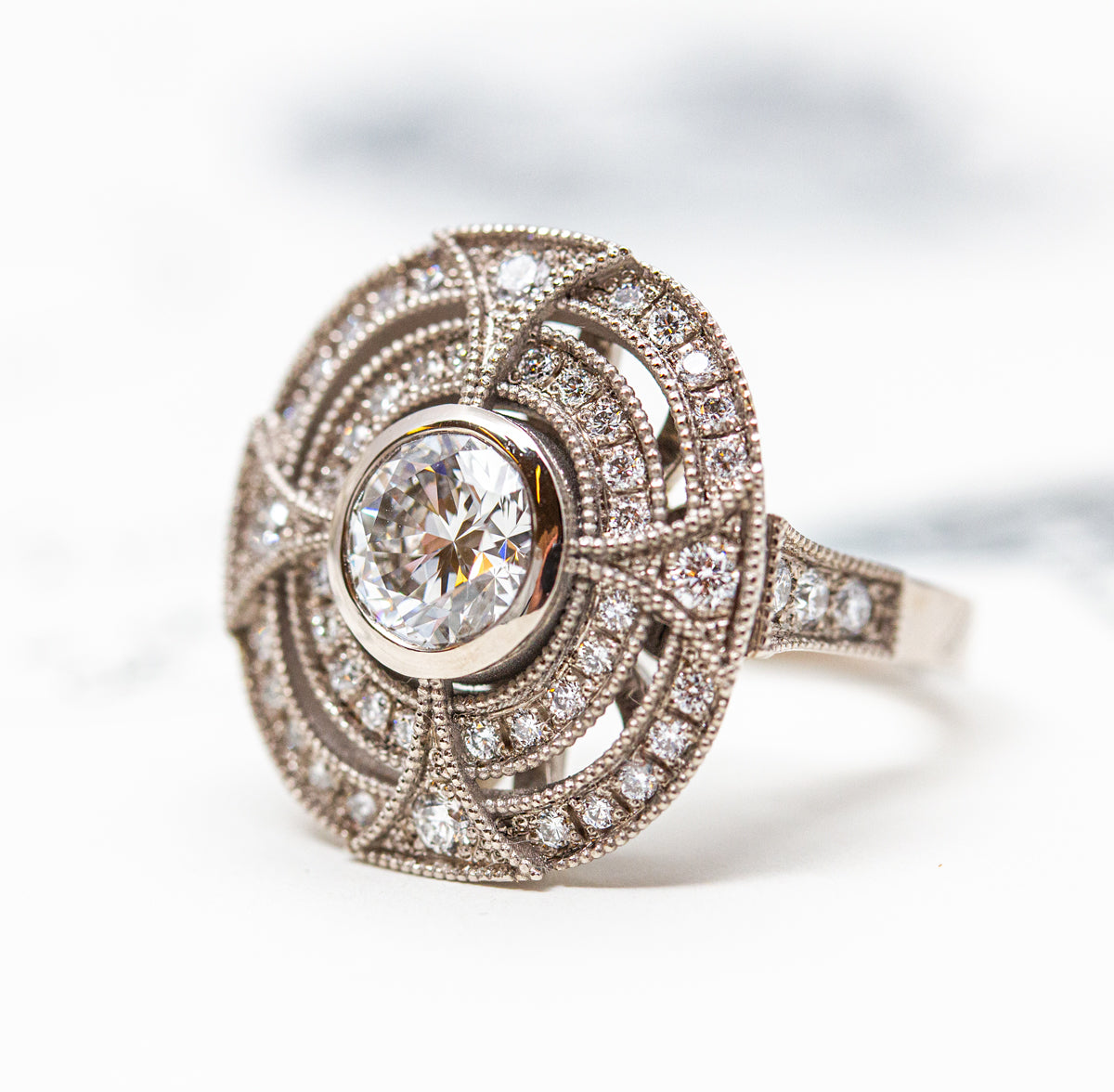 Bague entourage créée sur-mesure en or blanc 750/1000 Fairmined sertie d'un diamant central de 1,32ct et double cercle pavé de 46 diamants de synthèse
Création et fabrication en atelier de joaillerie éthique à Paris