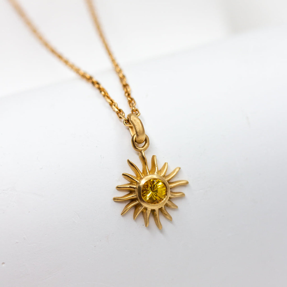 Pendentif Soleil serti d'un saphir jaune en or jaune 750/000 Fairmined, crée à la main par nos artisans joailliers à Paris.