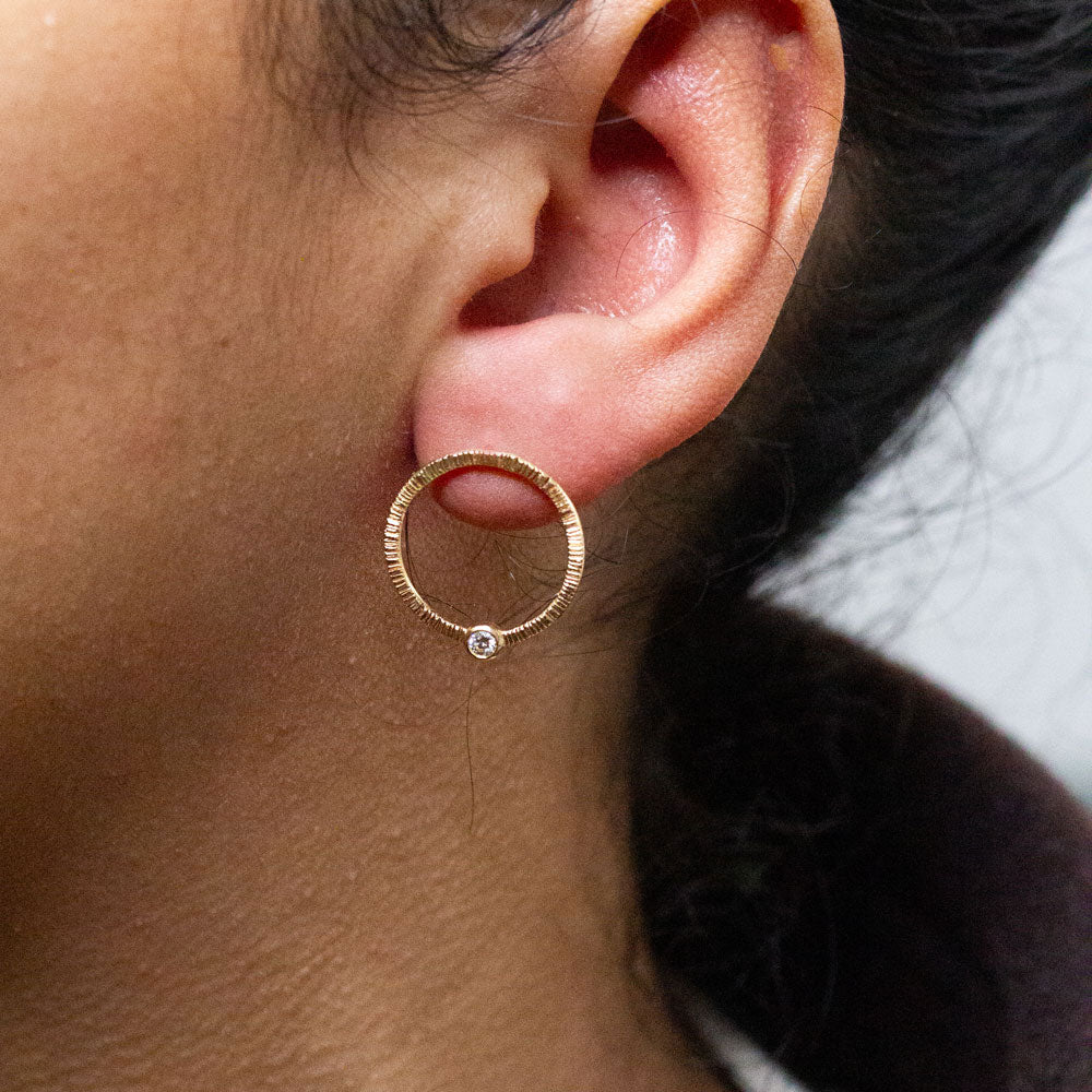 Boucles d'oreille cercle texturées en or éthique 18 carats Fairmined avec diamant de synthèse en son centre.