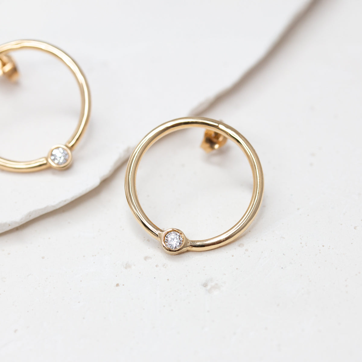 Boucles d’oreilles rondes en or jaune Fairmined 750/1000, qui se déposent délicatement sur le lobe, serties d’un diamant.