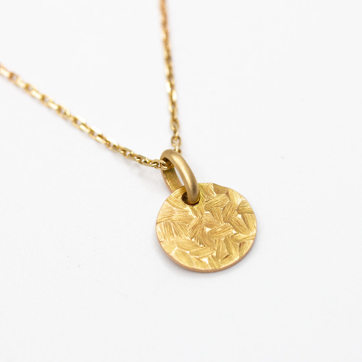 Médaille martelée et ronde de 10mm en or rose-champagne 750/1000 fabriquée artisanalement dans notre atelier de joaillerie éthique. Bijou à offrir pour les baptêmes, naissances, anniversaires
