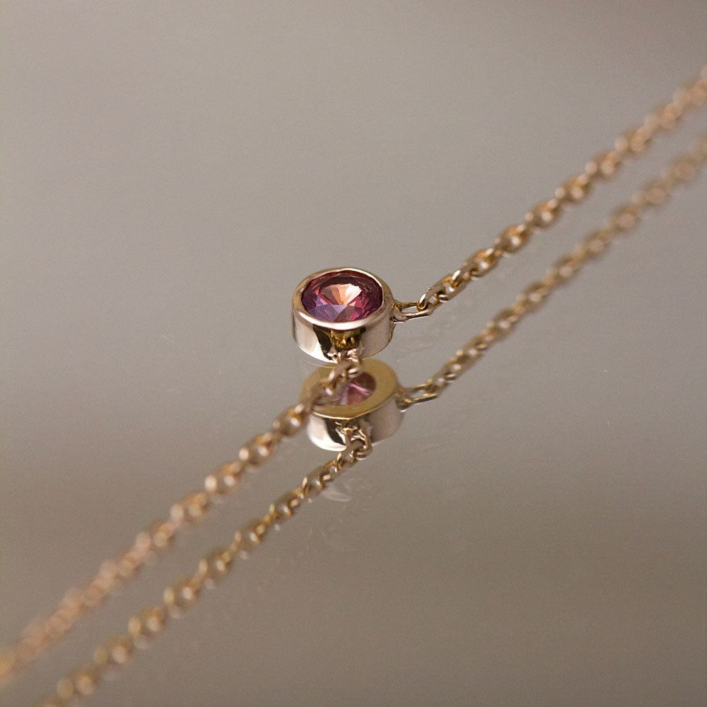 Collier en or éthique original orné d'un saphir rouge orangé lumineux.