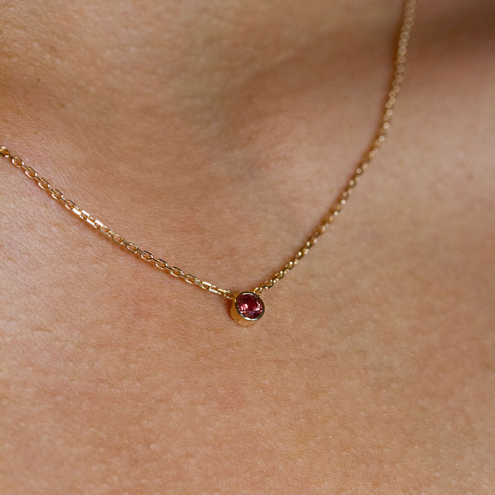 Un collier en or, agrémenté d'un saphir rouge, monté sur une délicate chaîne en or rose-champagne 18 carats certifié Fairmined.