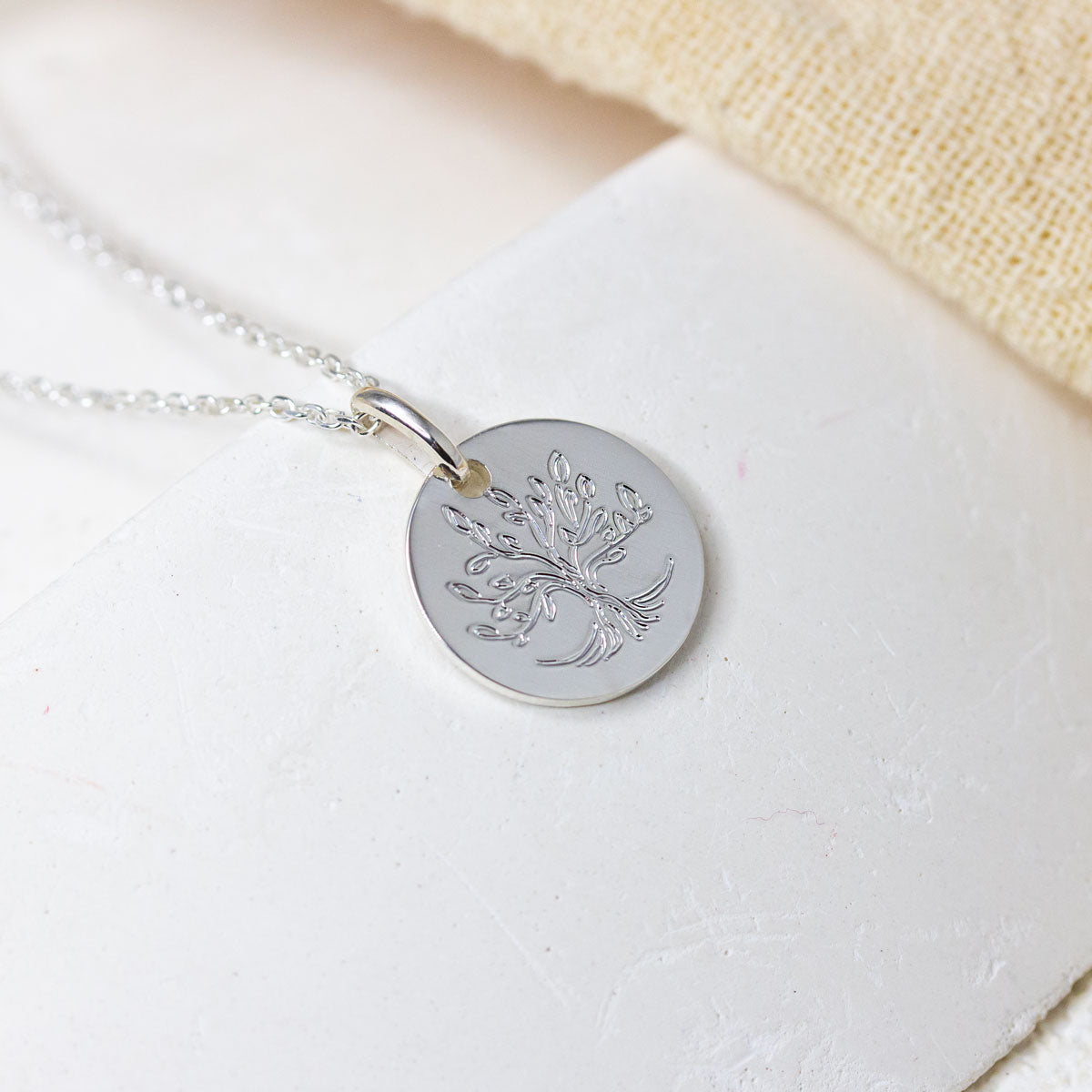 Médaille en or blanc gravé d'un arbre de vie.