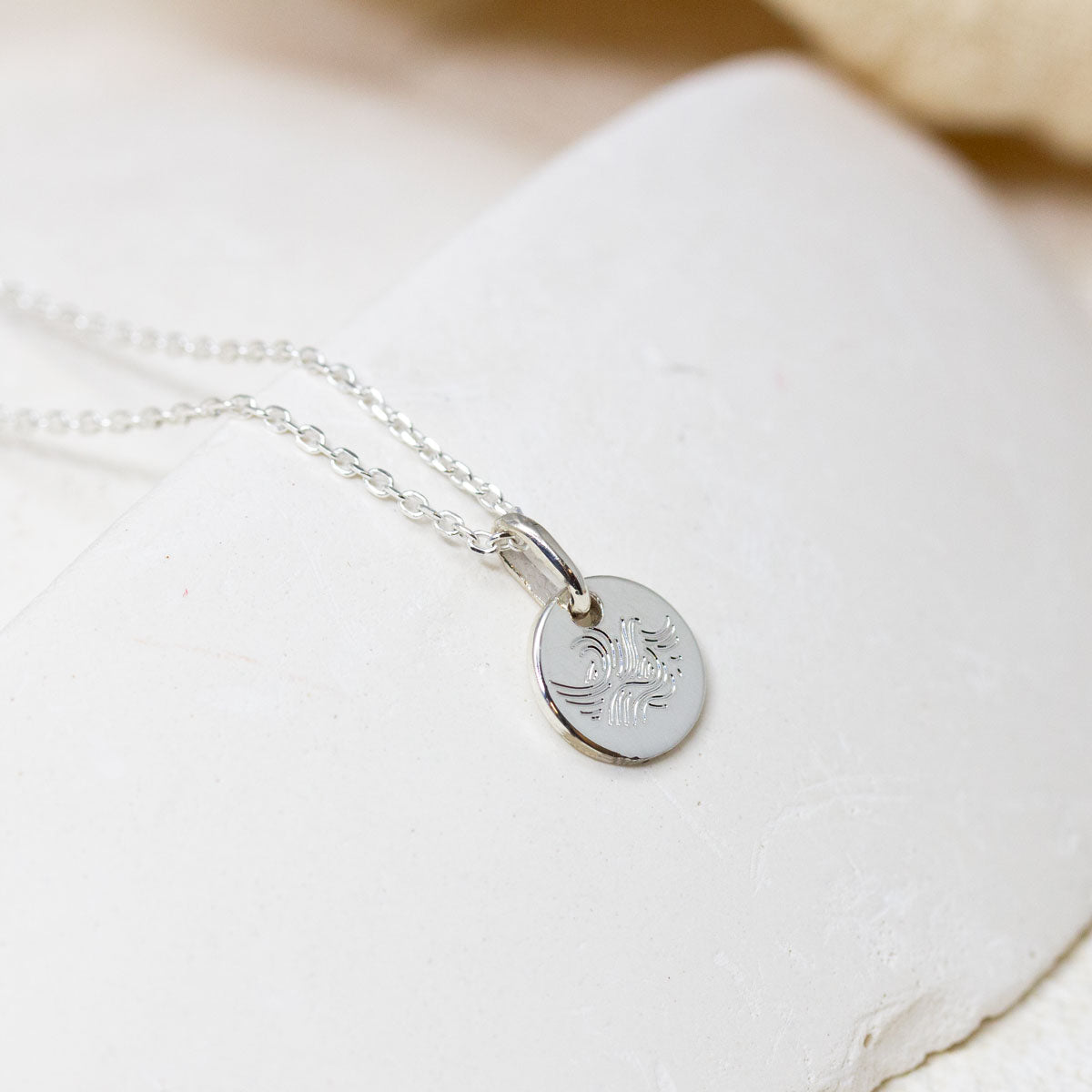 Médaille vague en or blanc Fairmined, joaillerie artisanale.