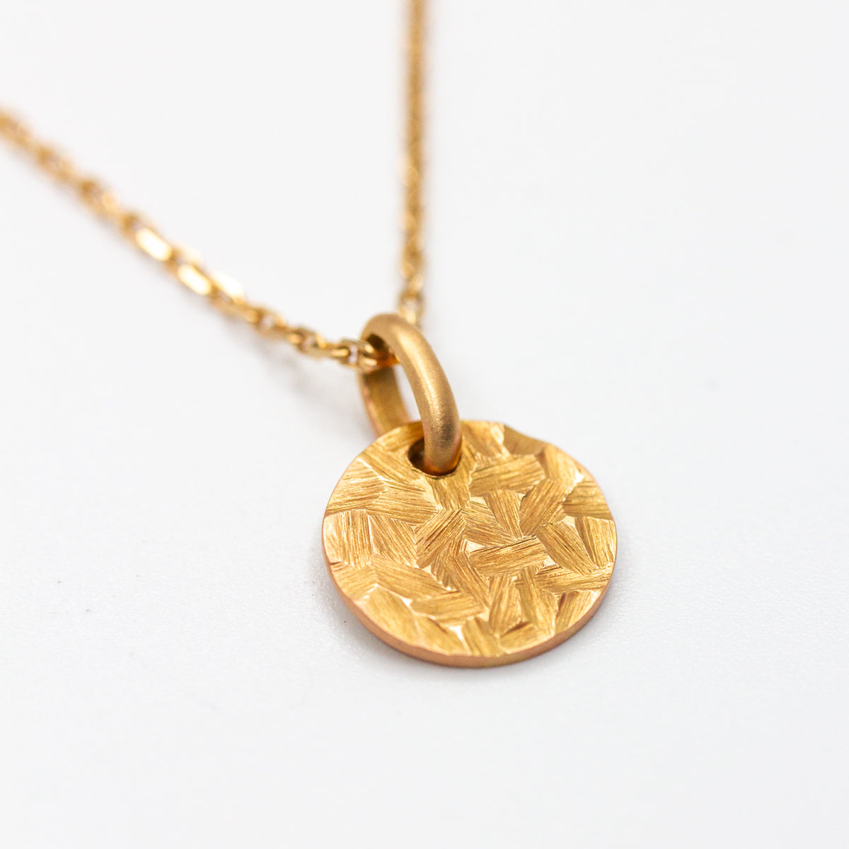 Médaille ronde de 10mm en or rouge 750/1000 martelé artisanalement dans notre atelier de joaillerie éthique. Bijou à offrir pour les baptêmes, naissances, anniversaires