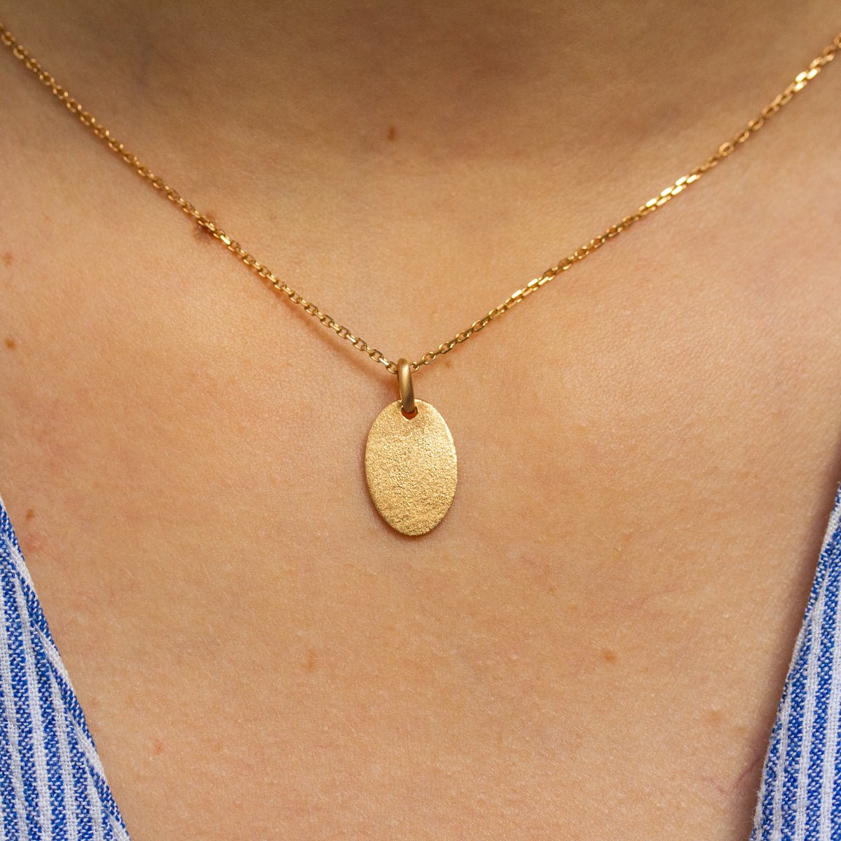 Médaille ovale en or jaune 18 carats recyclé texture sablée Gina pour femme, joaillerie éthique et fabrication artisanale à Paris. Gravure à personnaliser