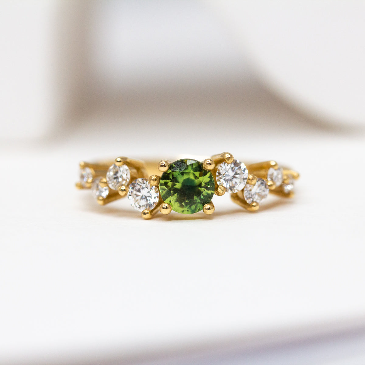 Pièce unique - Bague de fiançailles asymétrique en or jaune équitable 18 carats Fairmined, sertie d'un saphir vert rond de 4mm et de diamants de synthèse. Fabrication artisanale dans notre atelier de joaillerie à paris