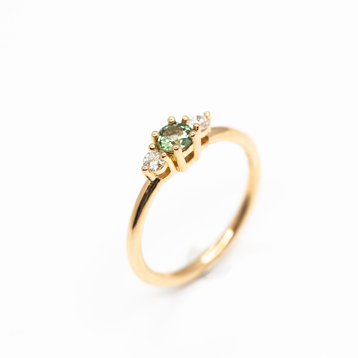 Bague de fiançailles épaulée femme Soleine en or jaune 18 carats recyclé  ornée d'un saphir vert et deux diamants de synthèse ronds. Réalisée à la main dans notre atelier de joaillerie à Paris