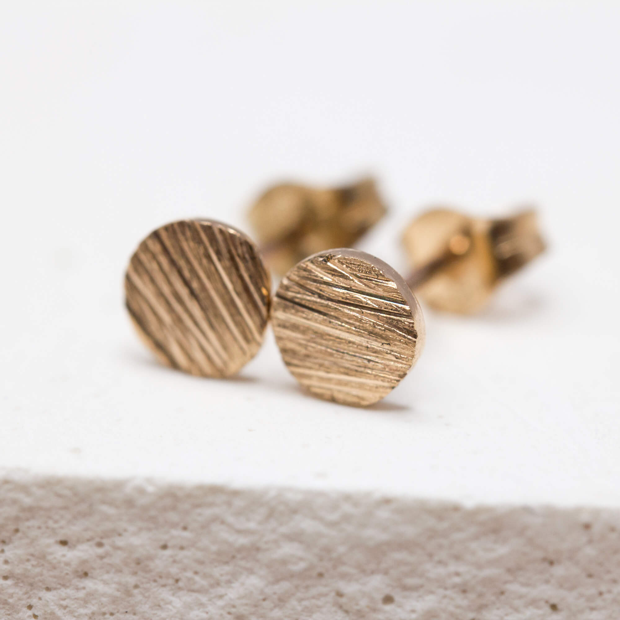 Paire de boucles d'oreille puces à la texture striée, en or rose-champagne 18 carats Fairmined, façonnée à la main dans notre atelier parisien.