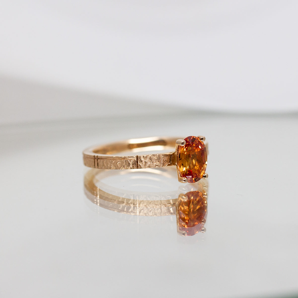 Bague originale sertie d'un saphir orange ovale sur un anneau texturé en or rose-champagne 18 carats